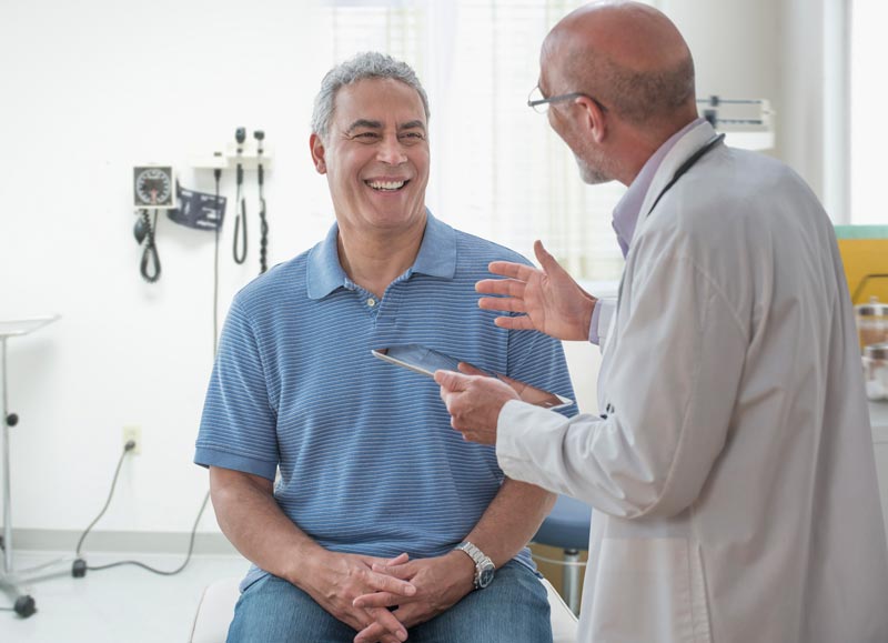Male doctor talking with smiling male patient