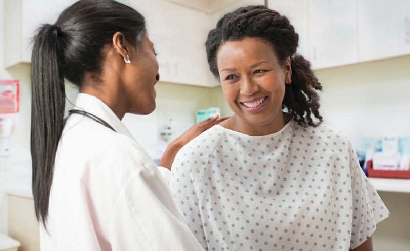 Female doctor talking with smiling female patient