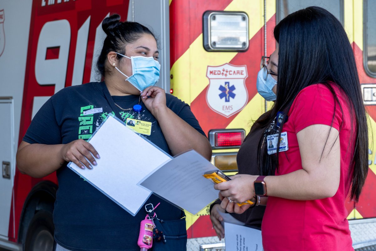 Three medical professionals wearing masks talk in a group