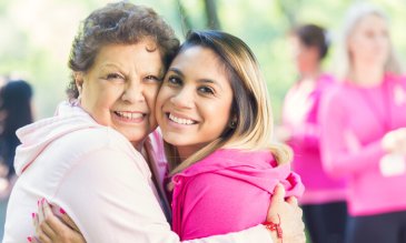 two women in pink, embracing at a breast cancer event