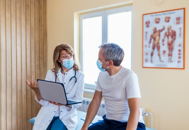 Médico y paciente con máscaras y hablando