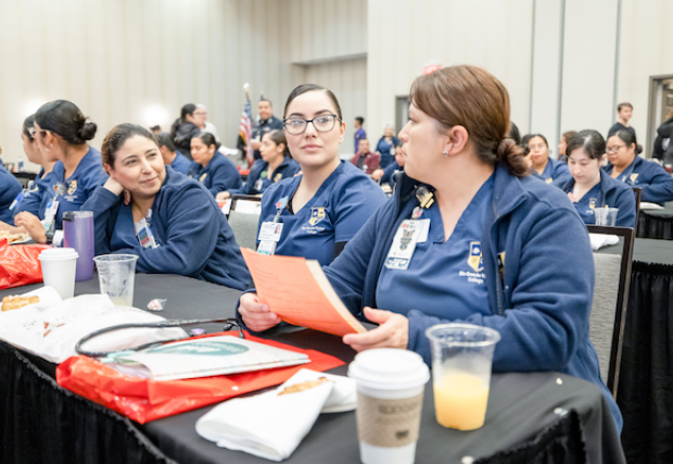 Three women listening to presentations during the symposium