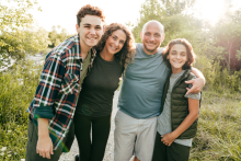 Father, mother and two sons smiling and standing in field