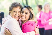 two women in pink, embracing at a breast cancer event