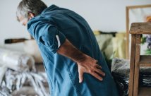 An older person holding their back in pain