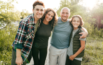 Father, mother and two sons smiling and standing in field