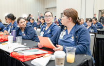 Three women listening to presentations during the symposium